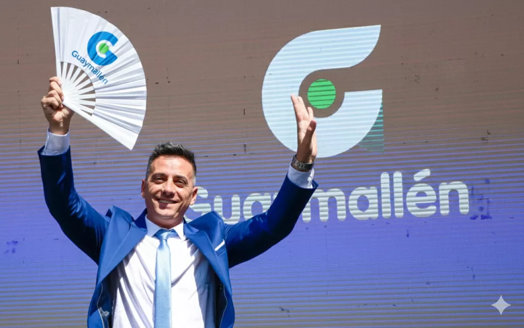 Representación IA del jefe comunal saludando con un abanico institucional de Guaymallén en escenario