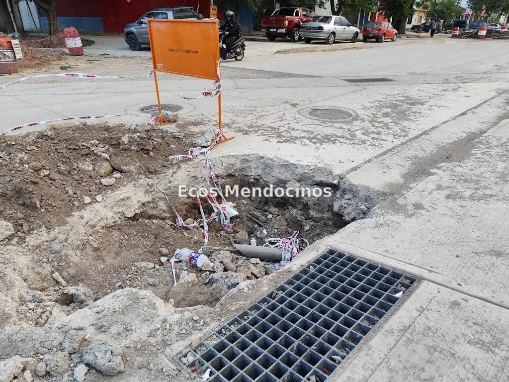 Hormigón nuevo abierto en avenida Mitre, Guaymallén, con caños expuestos, escombros y una excavación junto a una rejilla.